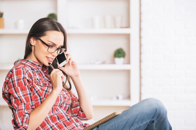 Linda garota no telefone tomando notas