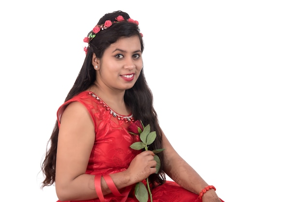 Linda garota ou mulher segurando e posando com uma flor rosa vermelha em branco