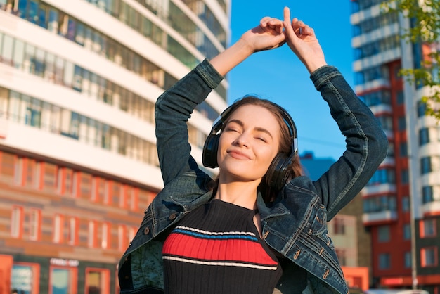 Foto linda garota ouvindo música em fones de ouvido estilo de rua ao ar livre