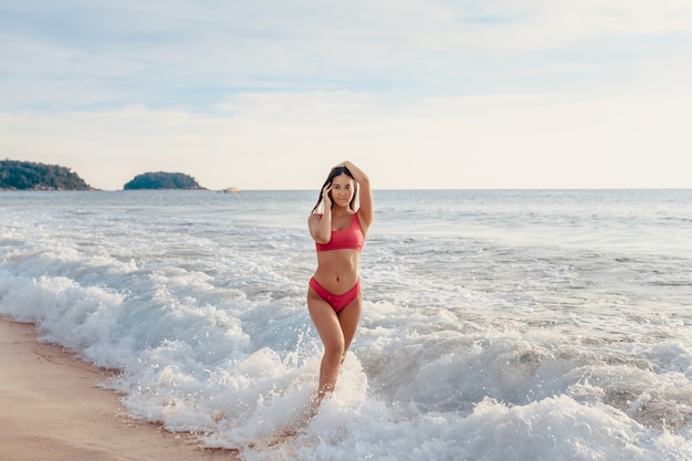 Linda garota parada nas ondas do mar branco na praia tropical