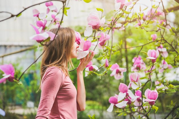 Linda garota perto da árvore florescendo Magnólia ao ar livre Clima de primavera Mulher relaxando