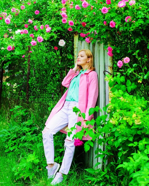 Linda garota perto de rosas cor de rosa sorrindo mulher no jardim florescendo primavera