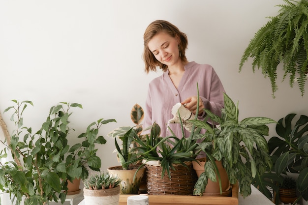 Linda garota regando lindas plantas verdes de interior que crescem em diferentes vasos