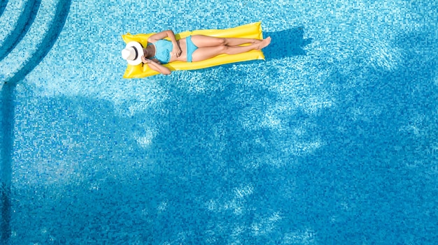 Linda garota relaxando na piscina, mulher no colchão inflável na água, vista aérea