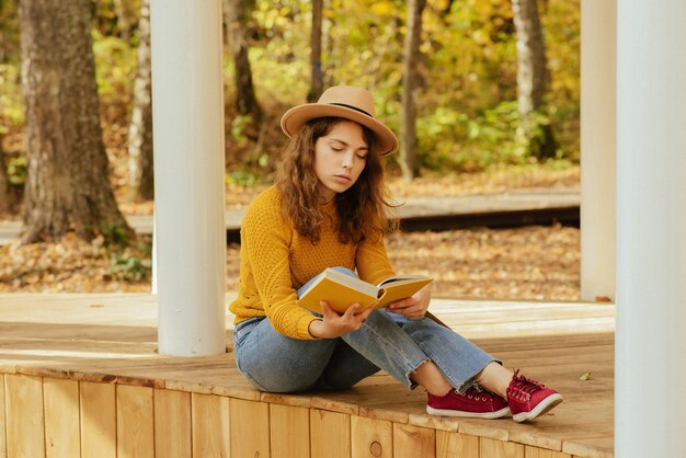 Linda garota relaxando no parque no outono com um livro