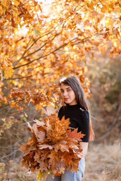 Linda garota ruiva com um buquê de folhas amarelas de outono