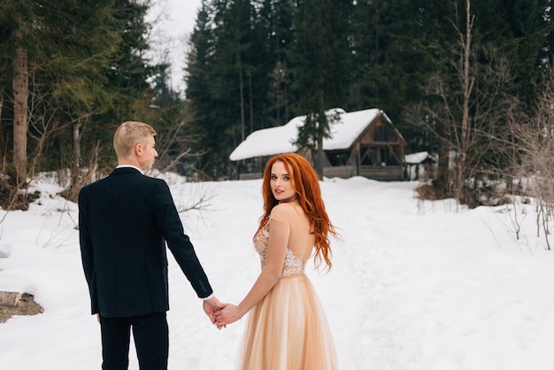 Linda garota ruiva com vestido de inverno, segurando a mão de um cara.