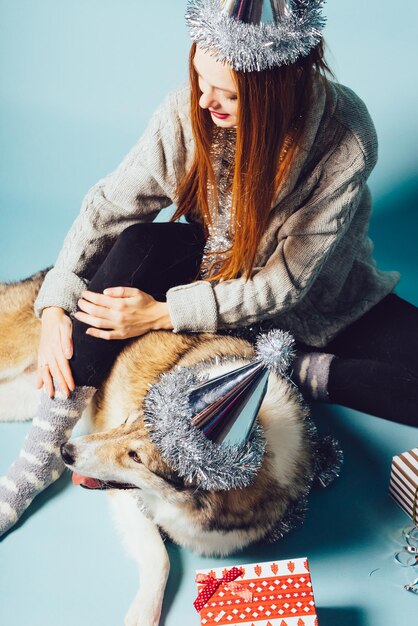 Linda garota ruiva em um boné celebra o ano novo e o Natal com seu cachorro grande