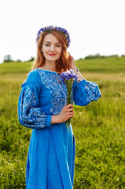 Linda garota ruiva em um vestido azul ucraniano com uma coroa na cabeça