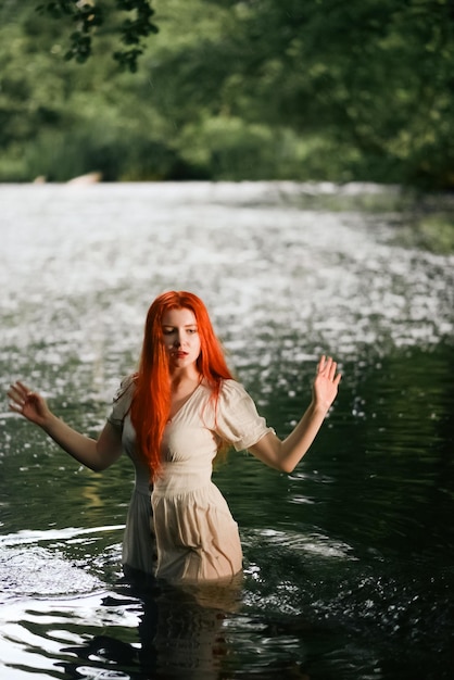 Foto linda garota ruiva em um vestido branco no lago