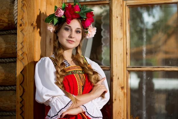 Linda garota Russa com uma foice e uma coroa na cabeça em vestido nacional.