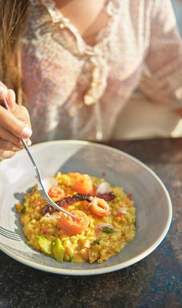 Foto linda garota saboreando um delicioso risoto com salmão defumado