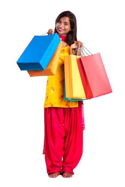 Linda garota segurando e posando com sacolas de compras em um fundo branco