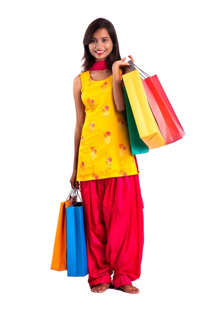 Linda garota segurando e posando com sacolas de compras em um fundo branco