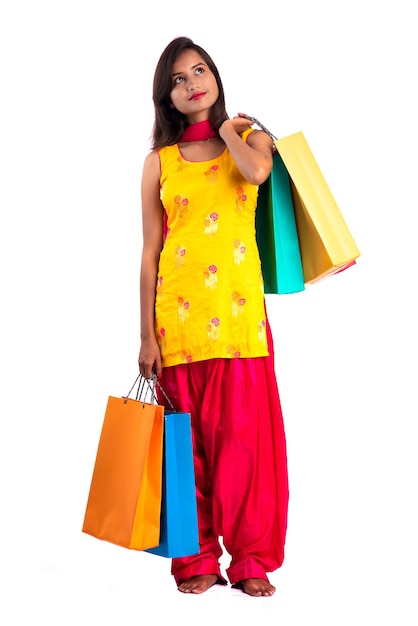 Linda garota segurando e posando com sacolas de compras em um fundo branco