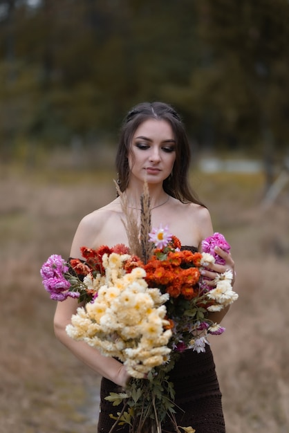 Linda garota segurando um buquê de flores na floresta