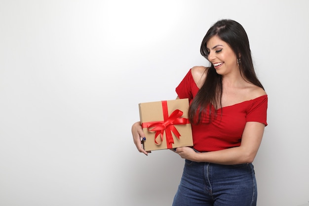 Linda garota segurando um presente do dia dos namorados no fundo branco