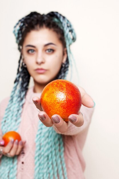 Linda garota segurando uma laranja vermelha