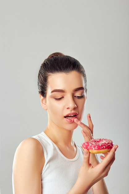 Linda garota segurando uma rosquinha rosa