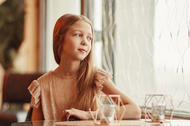 Linda garota sentada à mesa em um café