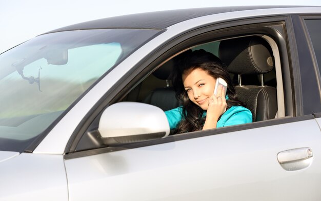 Linda garota sentada em um carro e falando ao telefone