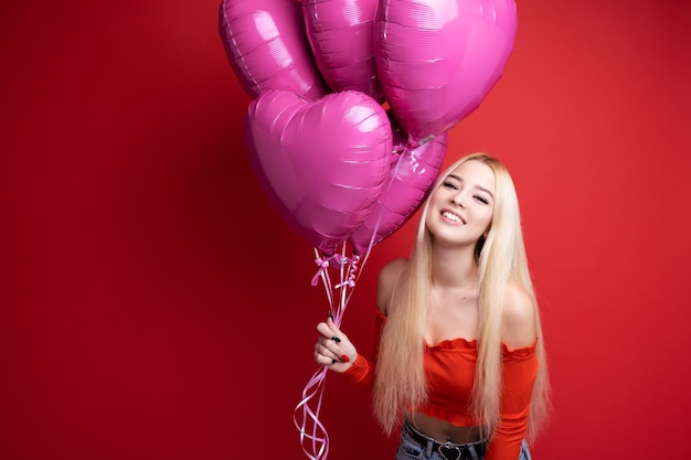 Linda garota sorridente com balões em vermelho