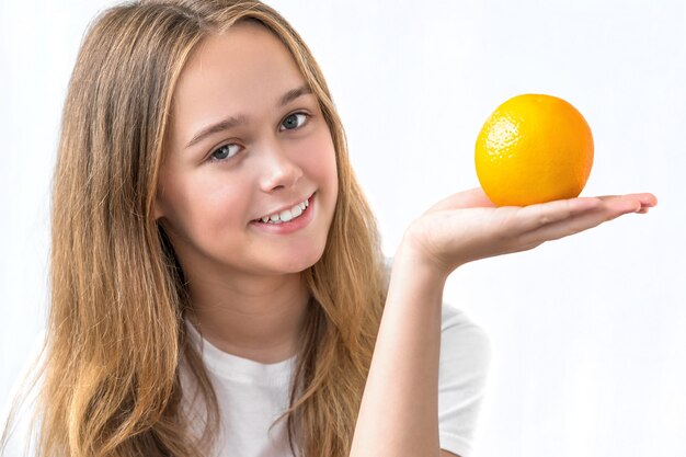 Foto linda garota sorridente com cabelo comprido em uma camisa branca, segurando laranja isolada no branco