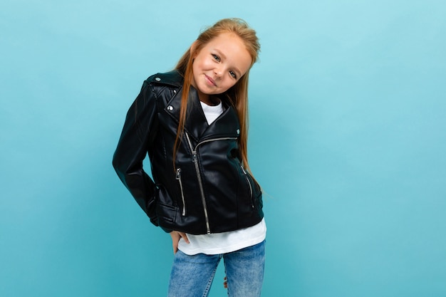 Linda garota sorridente em um look casual com uma jaqueta de couro e jeans posando