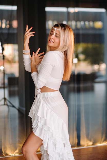 Linda garota sorridente em um vestido branco dançando no ginásio