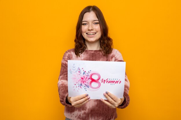 Foto linda garota sorridente no feliz dia da mulher segurando um cartão comemorativo