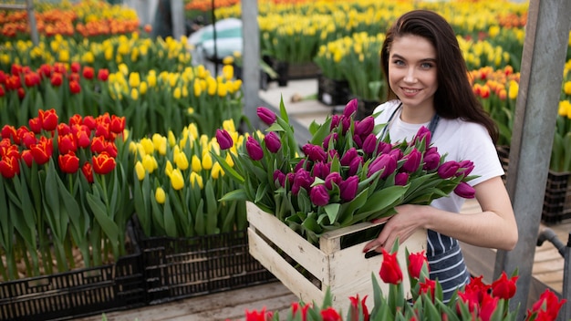 Linda garota sorridente, trabalhador com flores em estufa. trabalho de conceito na estufa, flores.