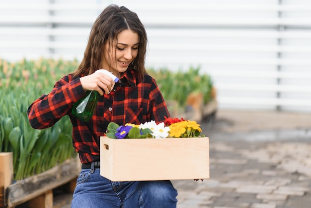 Linda garota sorridente, trabalhador com flores em estufa.