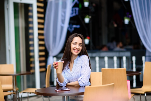 Linda garota sorrindo e bebendo café.