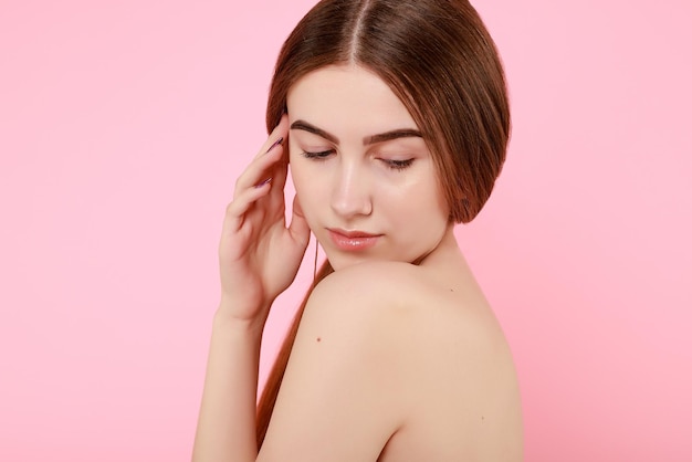 Linda garota tocando sua pele perfeita em fundo rosa conceito de cuidados com a pele retrato de mulher de beleza com pele limpa modelo de moda bonito de beleza com maquiagem natural em fundo rosa