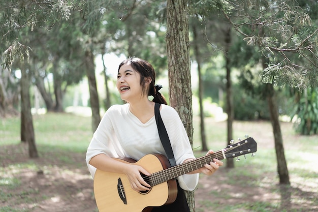 Linda garota tocando violão no jardim