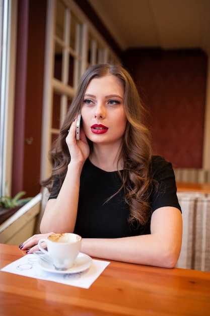 Linda garota tomando café e falando no telefone