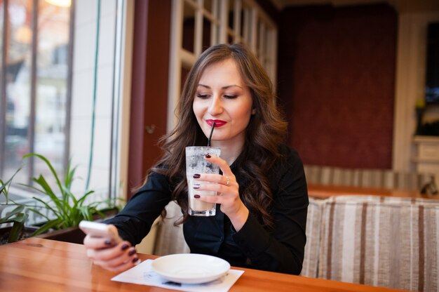 Linda garota tomando café e olhando no telefone