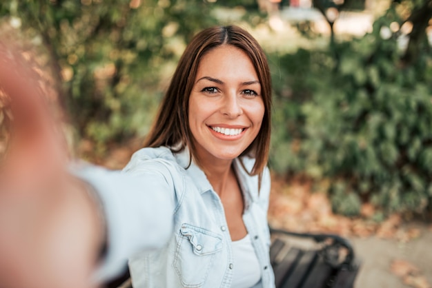 Foto linda garota tomando selfie no parque.