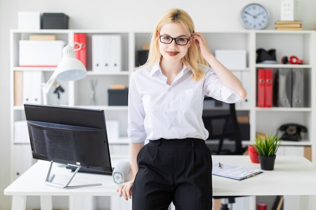 Linda garota, trabalhando em um escritório brilhante em uma mesa de computador.