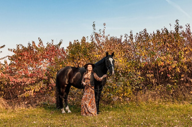 Linda garota, uma mulher caminha com uma estrada de outono de cavalo