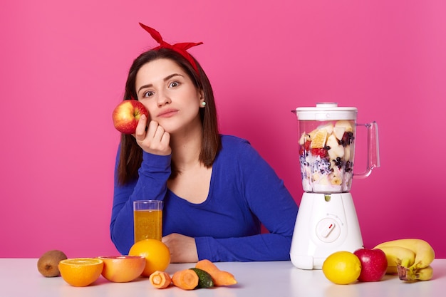 Linda garota usa camisola azul e com faixa de cabelo vermelha se senta à mesa e pensa em seus planos