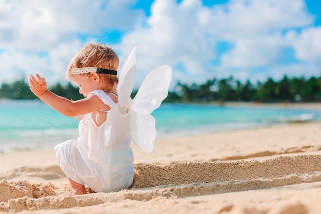Linda garota usando asas de anjo na praia