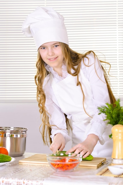 Linda garota vestindo uniforme de chef cozinhando na cozinha