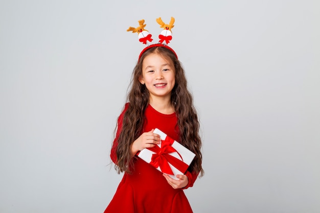 linda garotinha asiática em um vestido vermelho segurando uma caixa de presente espaço de texto de conceito de natal