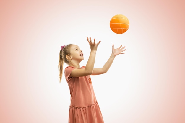 Linda garotinha bonitinha jogando bola no fundo rosa