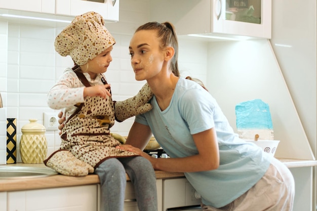 Linda garotinha caseira com sua linda mãe faz panquecas na cozinha branca