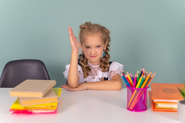 linda garotinha colegial fazendo lição de casa com livros na mesa