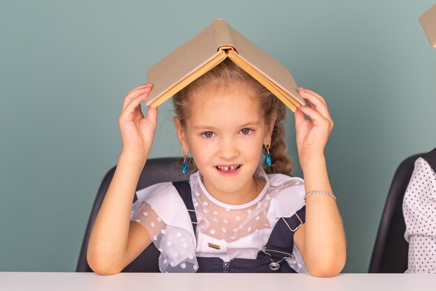 linda garotinha colegial fazendo lição de casa com livros na mesa