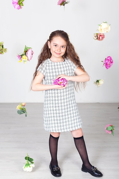 Linda garotinha com cabelo comprido em um vestido de pé e posando em um fundo branco no estúdio