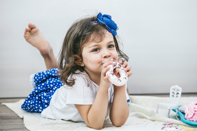 Linda garotinha com pratos de brinquedo, doces e bonecos brincando na festa do chá feliz